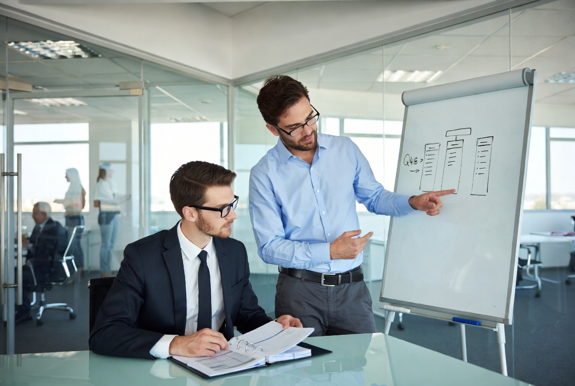 A CPA and a business owner mapping out a Q4 tax deduction strategy on a clean glass whiteboard
